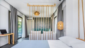 Una habitación de hotel moderna con una cama grande, un escritorio con una computadora portátil, una lámpara colgante y vistas al exterior.