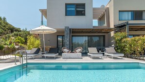 Un área de piscina moderna con sillones reclinables y una pérgola.