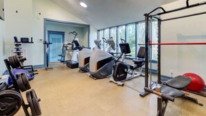 Ein Fitnessstudio mit Cardiogeräten, Gewichten und einem roten Trainingsball.