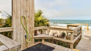 Eine Holzterrasse mit einer Holzkonstruktion, möglicherweise einer Dusche, und Blick auf den Ozean.