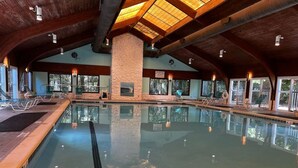 Ein Innenpool mit einer Steinsäule, Holzbalken und großen Fenstern.