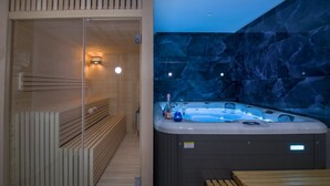 A modern spa room with a wooden sauna, a hot tub, and a stone wall. - Brand New Luxury villa★Sauna & Jacuzzi★Walk to Everything★Private Heated Pool (Galatas)