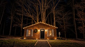 Une petite cabane en bois avec une porte d’entrée, deux fenêtres et une véranda.