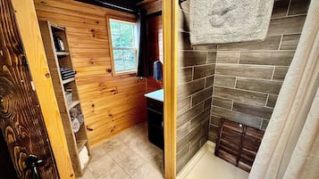 Een badkamer met houten wanden, een douchegedeelte en een raam.