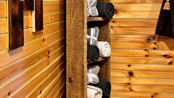 A wooden wall with a built-in shelf holding towels and toiletries.