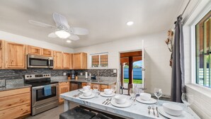 A modern kitchen with wooden cabinets, stainless steel appliances, and a marble countertop.