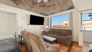 Ein Hotelzimmer mit Ziegeldecke, einem Flachbildfernseher, einer Couch, einem kleinen Tisch und einem Bett.