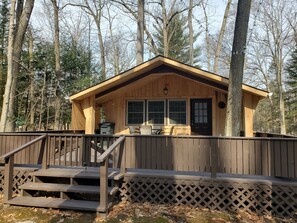 Een houten hut met een veranda, een tafeltje en een stoel.
