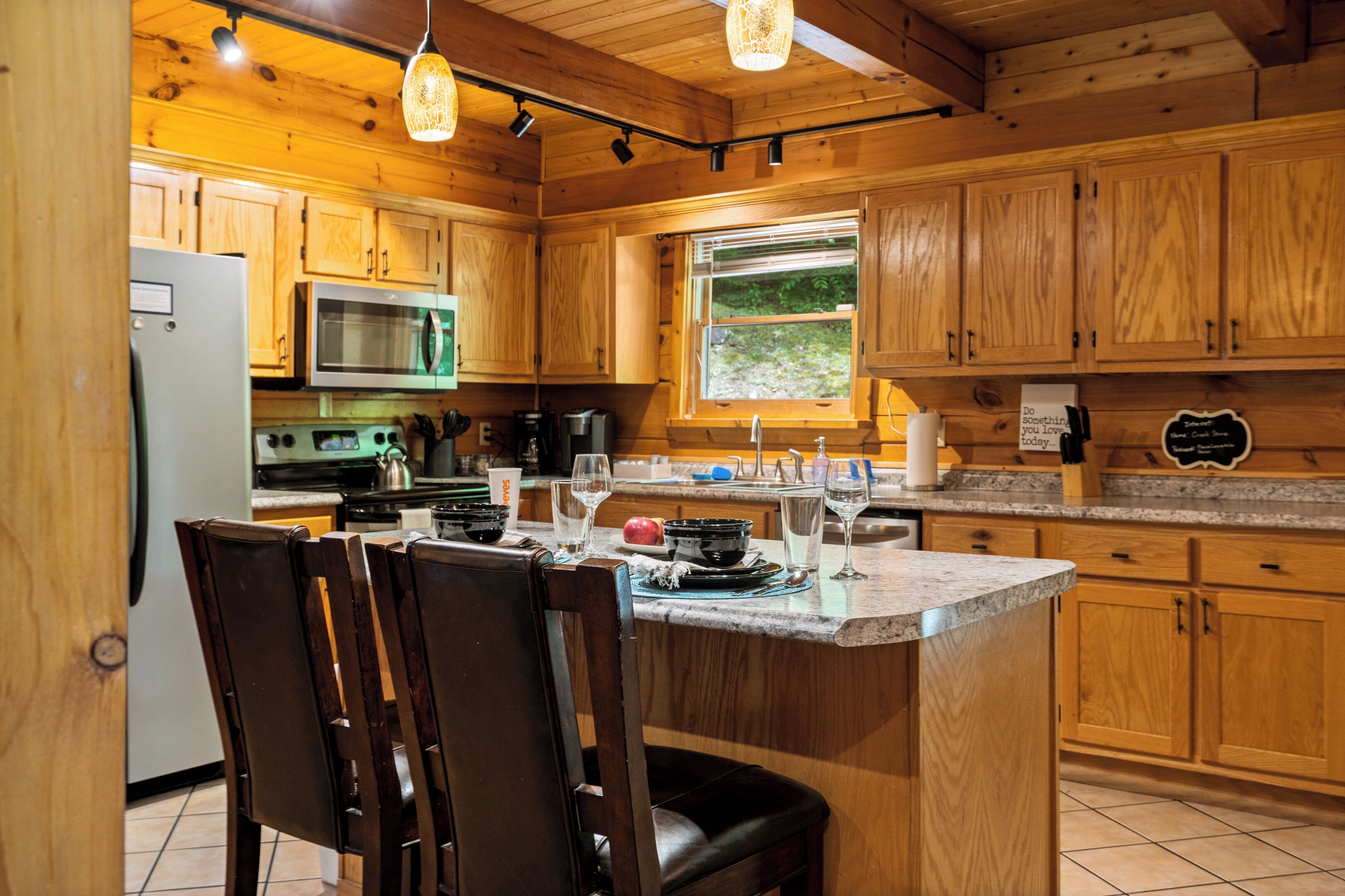A wooden kitchen with a central island, stainless steel appliances, and a window providing natural light.