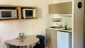 Een kleine keuken met een magnetron, broodrooster, spoelbak en koelkast.