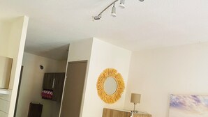 Een kamer met een rode bank, een houten garderobe, een spiegel en een wandlamp.