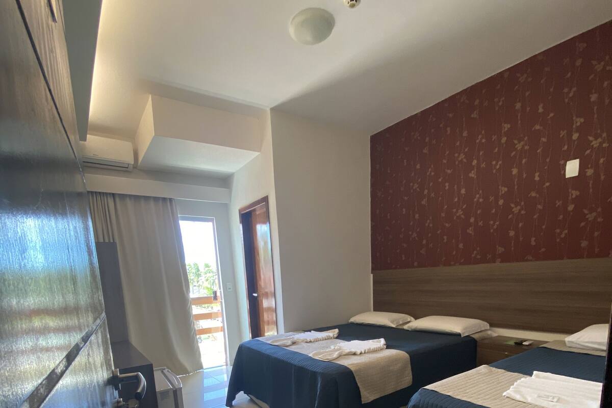 A hotel room with two beds, a wardrobe, and a bathroom.