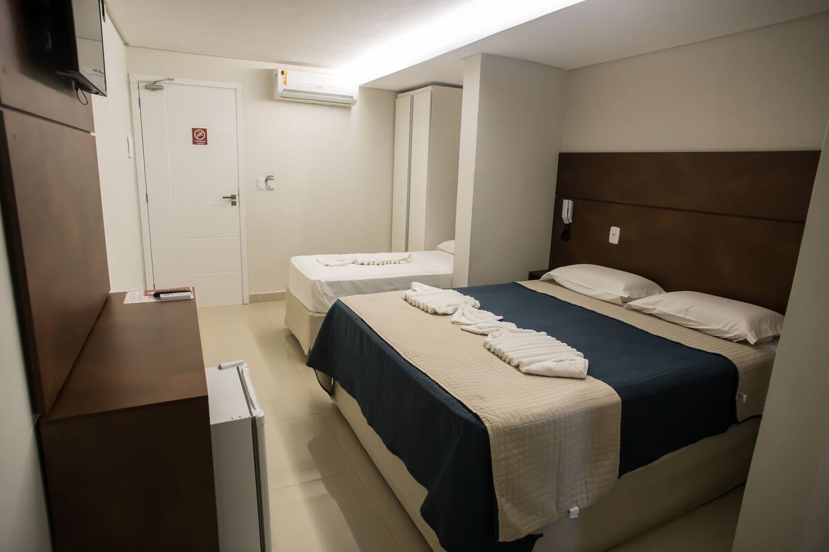 A hotel room with a bed, a desk, a chair, a wardrobe, and a bathroom.