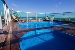 A rooftop pool area with two swimming pools, lounge chairs, and a glass railing overlooking the ocean. - Pousada Orla Dos Corais (Maragogi)