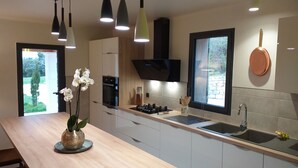 A modern kitchen with a wooden countertop, built-in oven, and a window with a view of greenery. - Stone house, private pool, panoramic view, close to the Gorges de l'Ardèche (Orgnac-l'Aven)