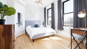 Una camera da letto moderna con un letto, una scrivania e un'ampia finestra.