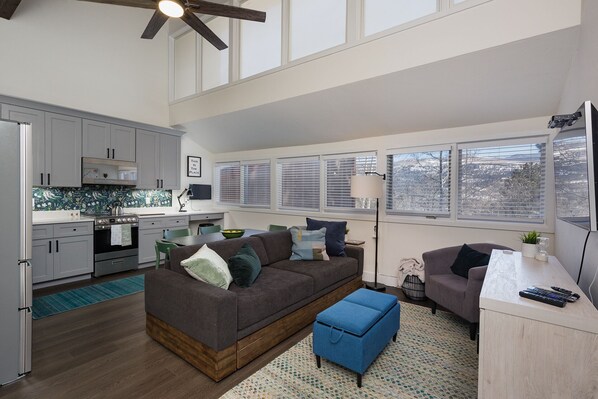 A modern kitchen with a dining area, a sofa, and a small table with a lamp. - The Green Canopy | AC, Pool, Hot Tub, Golf & Ski (Durango)