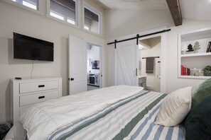 A bedroom with a bed, a TV, a wardrobe, and a bathroom visible through an open door. - The Green Canopy | AC, Pool, Hot Tub, Golf & Ski (Durango)