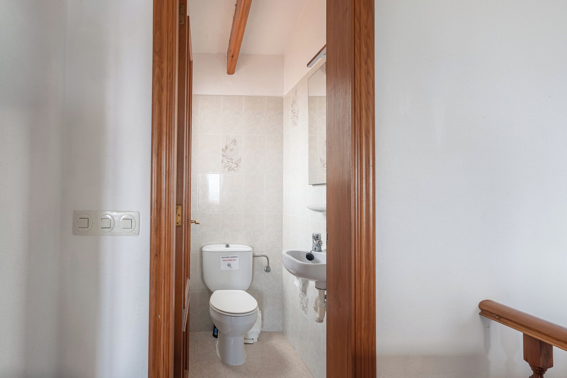 A small, clean bathroom with a toilet, sink, and wooden door frame.