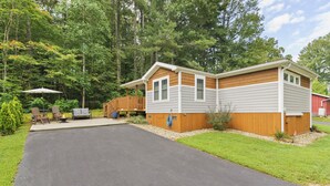 A two-story cabin with a covered patio area, a fire pit, and a wooden deck. - The Funky Fuji @Backyard Apple Cottages (Flat Rock)