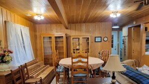 Ein Holzinterieur mit Esstisch, Stühlen, einer Couch und einer Lampe.