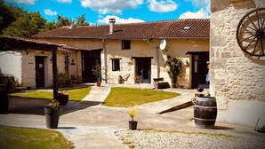 A courtyard with stone buildings, a wheelbarrow, and potted plants.