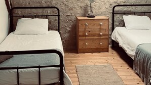 Un dormitorio con dos camas, un aparador de madera, un tragaluz y suelo de madera.