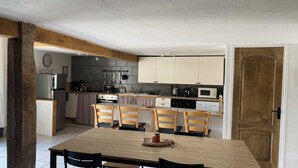 Una cocina compacta con armarios blancos, una mesa de madera y cuatro sillas.