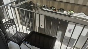 A balcony with a metal table and two chairs, a metal railing, and a view of the street below. - CASA CONCETTA (Napoli)