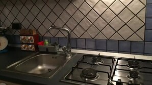 A kitchen with a sink, stove, and tiled backsplash. - CASA CONCETTA (Napoli)