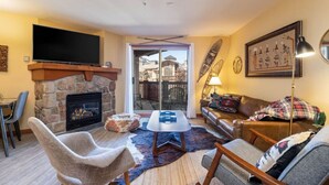 Una sala de estar con chimenea de piedra, un televisor de pantalla plana, un sofá y una mesa de centro.