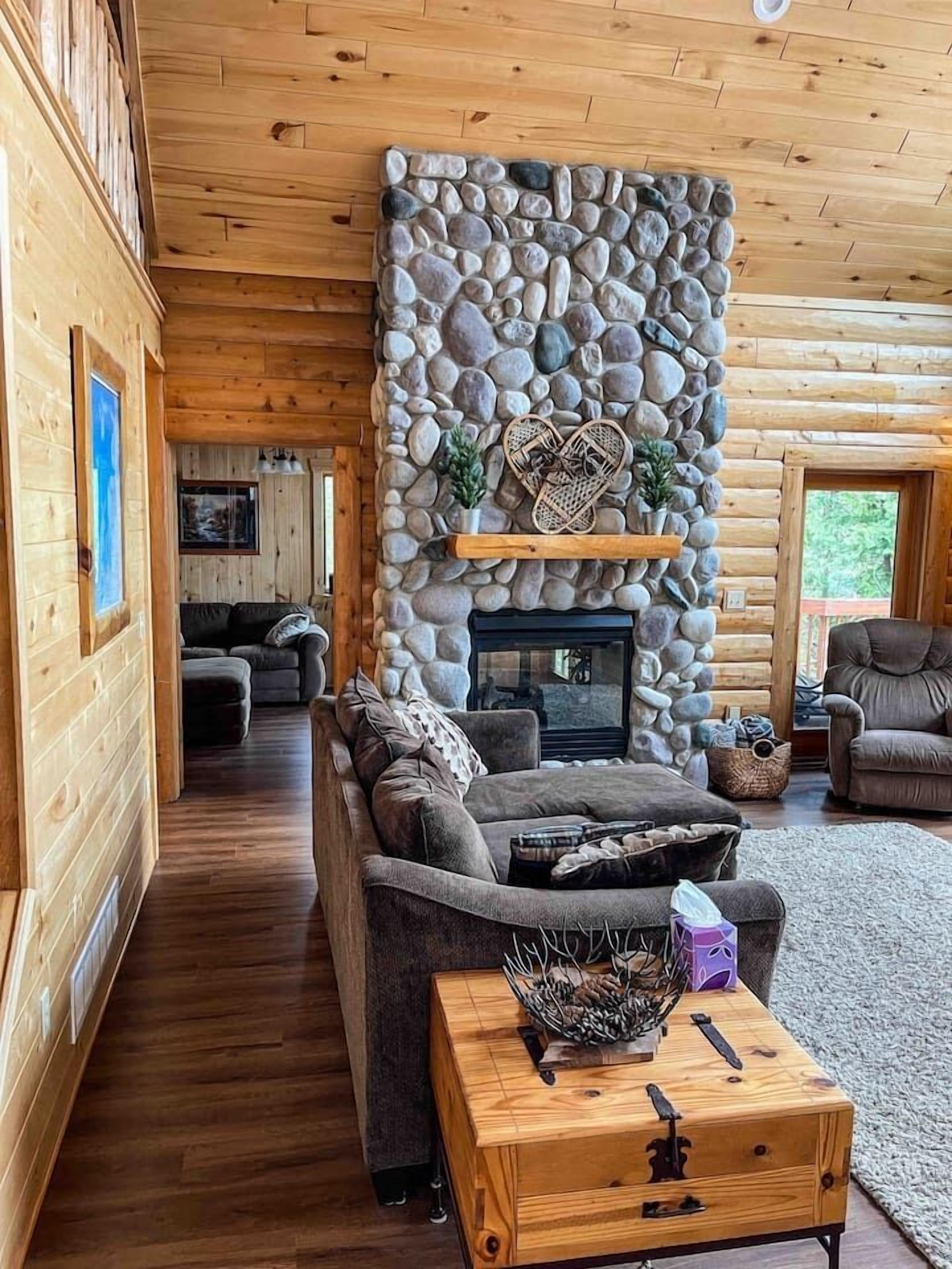 Ein gemütliches Blockhaus-Interieur mit Kamin, Holzwänden und einer komfortablen Sitzecke.