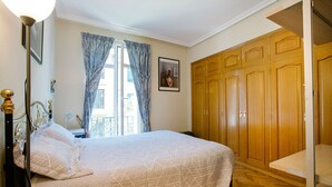 A bedroom with a bed, a wardrobe, a window with curtains, and a picture on the wall. - Select, Downtown, next to Avda., 5 min. walk to beaches and Old Town (Donostia)