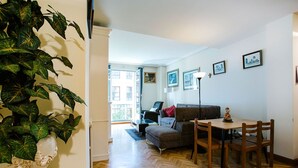 A living room with a sofa, a dining table with chairs, a potted plant, and a balcony with a railing. - Select, Downtown, next to Avda., 5 min. walk to beaches and Old Town (Donostia)