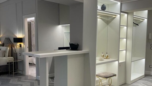 Un dormitorio moderno y bien iluminado con una cama grande, un escritorio y un vestidor.