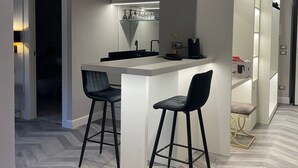 Una cocina moderna con una isla central, dos taburetes de bar y una alacena empotrada para vinos.