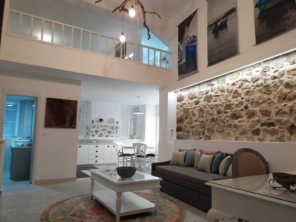 A spacious living area with a dining table, sofa, and a stone wall.