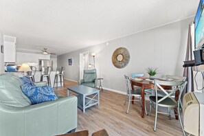 A modern living room with a sofa, coffee table, and dining area.