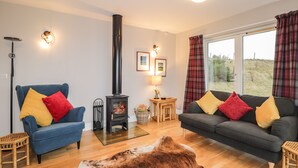 Una sala de estar con sofá, sillón y chimenea.