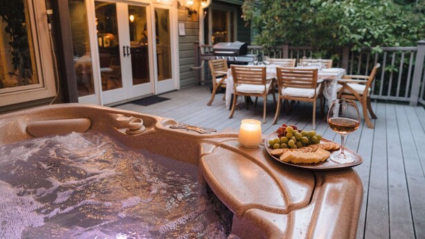 A hot tub with a wooden deck, outdoor seating, and a candle. - Luxury Home, Hot Tub Walk To Downtown Nevada City (Nevada City)
