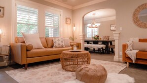 A living room with a sofa, ottoman, and a dining area with a table and chairs. - Luxury Home, Hot Tub Walk To Downtown Nevada City (Nevada City)