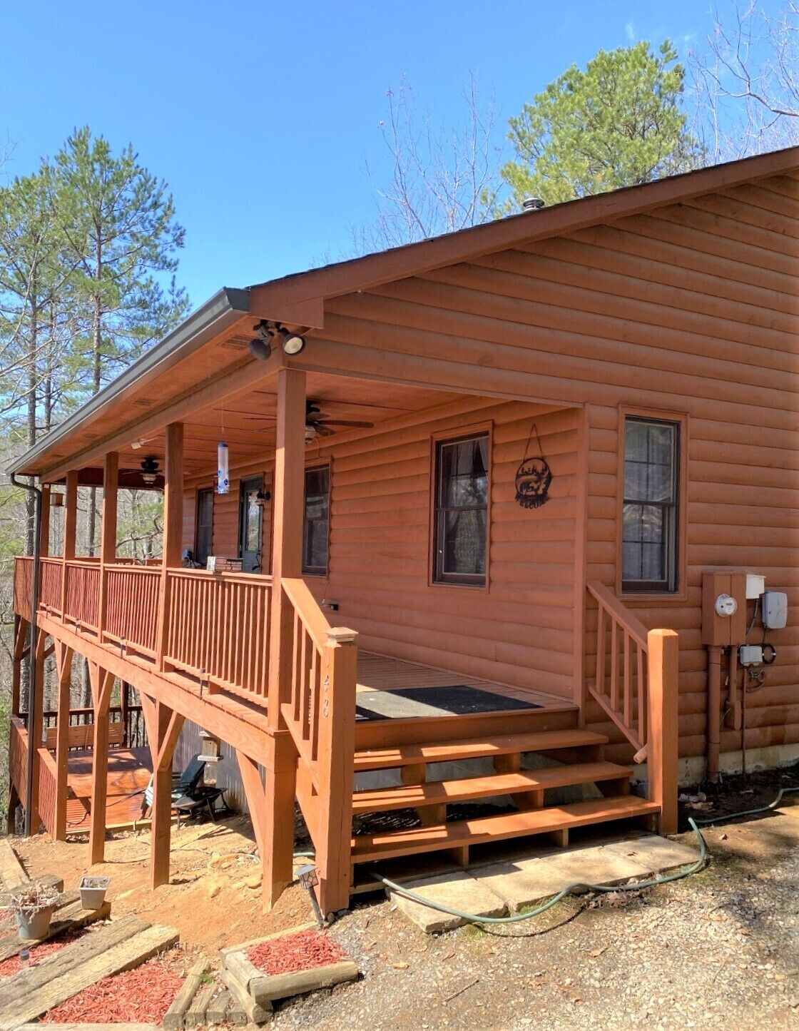 A wooden cabin with a covered porch, a front door, and a small front yard.