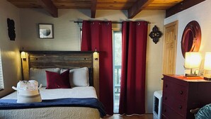 Une chambre à coucher avec un lit en bois, des rideaux rouges, une commode et un miroir.
