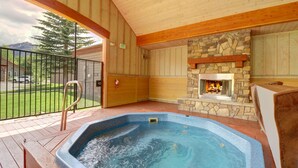 A hot tub with a stone fireplace, wooden deck, and a view of a mountain and trees. - Remodeled Mountain Retreat, Views, Frisco Location, Hot Tub, 2BR + Loft (Frisco)