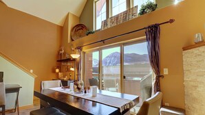A dining area with a long table, chairs, and a view of mountains through large windows. - Remodeled Mountain Retreat, Views, Frisco Location, Hot Tub, 2BR + Loft (Frisco)