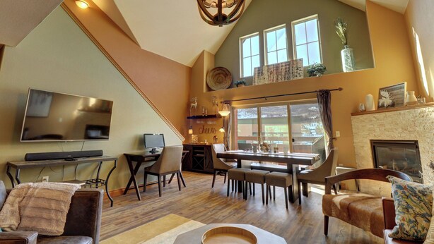 A spacious living area with a high ceiling, a fireplace, a dining table, and a television. - Remodeled Mountain Retreat, Views, Frisco Location, Hot Tub, 2BR + Loft (Frisco)