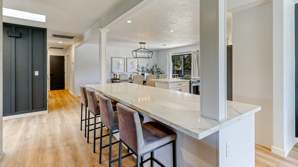 A modern kitchen with a large island, bar stools, and pendant lighting. - ***Pineland Place*** (Redding)