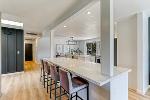 A modern kitchen with a large island, bar stools, and pendant lighting. - ***Pineland Place*** (Redding)