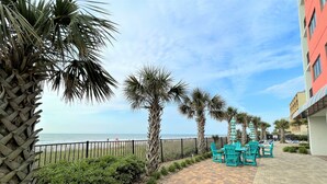 Un espace extérieur aménagé avec des meubles de jardin, des palmiers et une vue sur la plage.