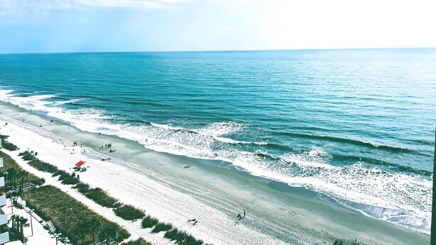 Une plage offrant une vue dégagée sur l’océan et bordée d’un rivage sablonneux.